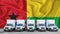 Guinea Bissau flag in the background. Five new white trucks are parked in the parking lot. Truck, transport, freight transport.