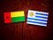 Guinea Bissau flag with Uruguaian flag on a tree stump isolated