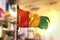 Guinea Flag Against City Blurred Background At Sunrise Backlight