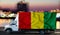 Guinea flag on the side of a white van against the backdrop of a blurred city and river. Logistics concept