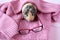 The Guinea pig is sitting on a pink sweater and red glasses