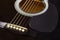 Guitar black, polished smooth soundboard with protective plate, stretched strings, lower threshold, close-up selective focus