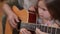 Guitar fretboard with blurred focused girl learning playing string instrument. Unrecognizable senior man teaching music