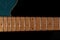 Guitar neck at the 12th fret. Maple fretboard portion on blue glitter electric guitar