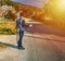 Guitar player hitchhiking on the edge of a country road at sunset