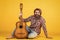 Guitar player on yellow background. Cheerful guitarist. charismatic mature man playing guitar while sitting. relax with