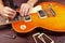 Guitar repairman checking the height of strings on electric guitar at workplace