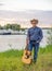 The guitarist of the country singer stands against the sky of the field. Rustic style. Summer vacation.