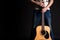 Guitarist holding two hands with an acoustic guitar on a black isolated background