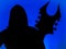 Guitarist with hood and a pointed Heavy Metal guitar with horned headstock on blue background