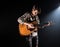 Guitarist, music. A young man plays an acoustic guitar on a black isolated background