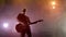 The guitarist performs on stage. Stage light, smoke.