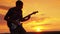 Guitarist play rock in the sunset on a warm summer