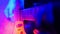 Guitarist plays on his guitar in bright neon lighting. The smoke machine starts working and the room fills up with smoke