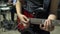 Guitarist with a red electric guitar plays funky music with drummer on the street. Male hands takes a chord on guitar