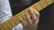 Guitarist's fingers on neck of a six-string electric guitar