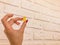 A gummy yellow bear in the hands of a girl with a red manicure. bear are kept on a white brick background. homemade wall with