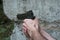 A gun in the hand of a Caucasian man against a brick wall of an rocks. Shooter with a gun of dark green