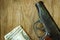 The gun and money on wooden table.