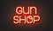 Guns shop neon sign on brick wall background.