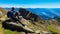 Gurglitzen - Hiker man sitting on rock on alpine meadow with panoramic view of lake Millstatt. Idyllic hiking trail