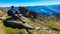 Gurglitzen - Hiker man sitting on rock on alpine meadow with panoramic view of lake Millstatt. Idyllic hiking trail