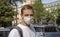 A guy 20-25 years old in a medical mask against the background of a European city. Concept: studying in Europe, the beginning of t