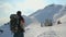 Guy with backpack going towards cableway, looking up at mountain