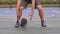 A guy basketball player dribbling ball between his legs at outdoor court. An athlete in a gray sports uniform hits the
