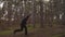 A guy in black clothes runs through forest between the trees, jumping over logs