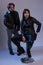 A guy in black leather clothes is standing next to a girl sitting on a bar stool. Studio photosession. Modern fashionable stylish