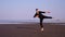 Guy in black performs classic ballet dance on empty beach