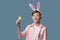 Guy with bunny ears with colorful Easter eggs in his hand in pink shirt.