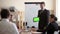 Guy Caucasian appearance in a jacket and tie holding a tablet with a green screen, standing near the whiteboard with a