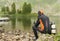 A guy in a diver suit is sitting on rocks on the lake shore