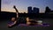 A guy does yoga on a fitness mat at sunset.