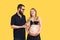 the guy draws with cream emoji on the belly of his pregnant wife on a yellow background