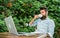 Guy drinks coffee relaxing terrace branches background. Man bearded hipster make pause for drink coffee and relax while