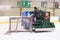 Guy driving an ice resurfacer while pulling the hockey net