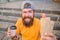 Guy eating hot dog. Man bearded eat tasty sausage and drink paper cup. Street food concept. Urban lifestyle nutrition