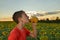 The guy eats honey from a jar against the background of a field with sunflowers and the evening sky. Beekeeping concept