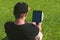 The guy is engaged in online training, on a green lawn with a tablet
