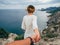 Guy follows a beautiful girl holding her hand in the tourist journey to the edge of the mountain against the sea