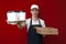 Guy a food delivery uniform in uniform gives coffee and pizza boxes on a red background, food delivery service worker