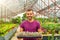 Guy gardener holds a pallet with many seedlings of cacti, mammillaria. Growing and caring for plants and flowers in a greenhouse,