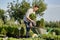 Guy gardener puts the seedlings in pots in a cart on the garden path in the wonderful nursery-garden on a sunny day