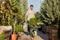 Guy gardener rolls a cart with seedlings in pots along the garden path in the wonderful nursery-garden on a warm sunny