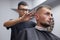 Guy get a haircut in a barbershop, a young Kazakh barber cuts manually with scissors and a comb, the master makes a short haircut