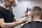 Guy get a haircut in a barbershop, a young Kazakh barber cuts manually with scissors and a comb, the master makes a short haircut