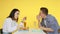 A guy and a girl on a date eat fast food and drink drinks from glasses on a yellow background. Date. The concept of